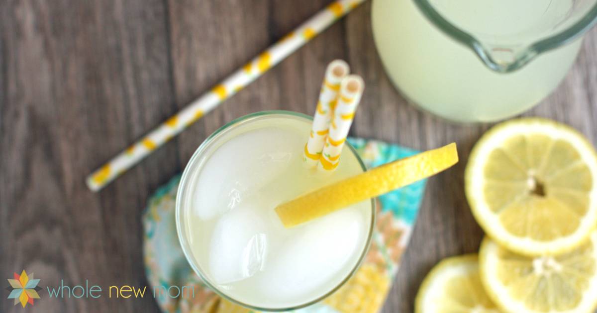 Top view of lemonade in a glass garnished with a slice of lemon and two straws with some slices of lemon scattered around