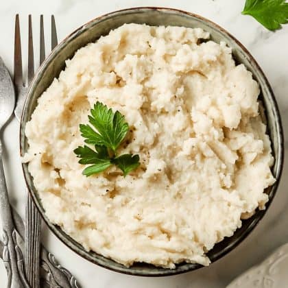 keto mashed potatoes in black bowl with parsley garnish