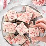 hand taking a piece of homemade sugar-free peppermint bark off a plate.