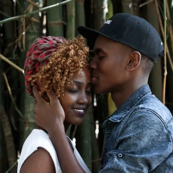 Man kissing a woman on the forehead.