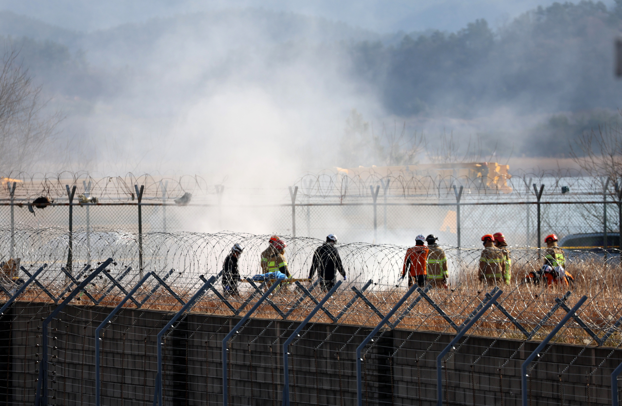 Rescue workers at the scene of the Jeju Air crash landing at Muan International Airport in South Jeolla Province, Sunday morning (Yonhap)