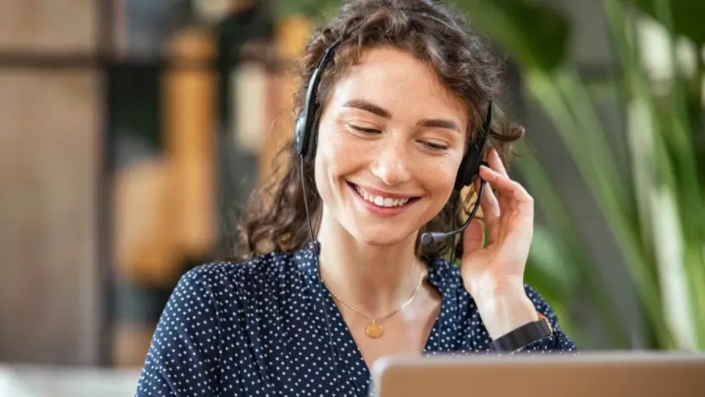 Mulher com um fone de ouvido pressionando um lado do fone para baixo.