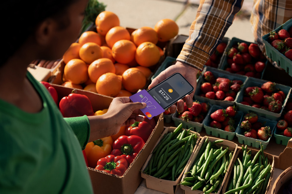 A customer holds their credit card up to a merchant’s iPhone to pay for goods.