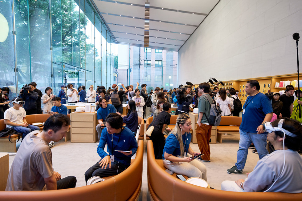 鏡頭拉遠拍攝的照片，顯示熱鬧的 Apple 表參道零售店內有著數十名顧客和團隊成員。