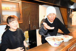 カウンターにラーメンを出す冨田佳浩さんと佐登子さん。知り合いの客にメニューにはないチャーハンもつくった=2024年12月25日、岐阜県高山市八軒町2丁目、荻野好弘撮影