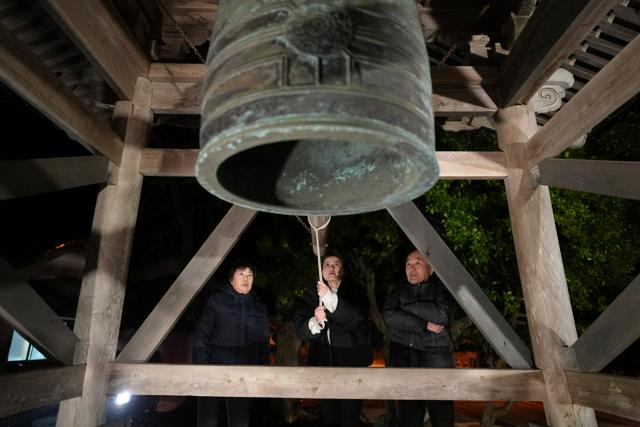 除夜の鐘を鳴らす専念寺の（右から）畠山義邦住職、次女の慶子さん、妻の由美子さん=2025年1月1日午前0時2分、石川県珠洲市三崎町寺家、西岡臣撮影