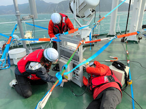 能登半島地震の発生を受け、輪島市の沖合に停泊したケーブル敷設船「きずな」のデッキで基地局設置の作業をするNTTドコモの技術者ら=2024年1月6日、NTTドコモ提供