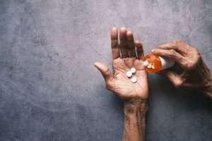 Hand holding pills with gray backdrop 