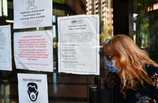 A woman wearing a facemask enters a building where the Employment Development Department has its offices in Los Angeles, California on May 4, 2020, past a posted sign mentioning the closure of the offices's public access counters due to the coronavirus pandemic. - Dismal US employment figures are expected with the release Friday May 8 of figures for April's US jobs report, with 30 million Americans filing for unemployment in the last six weeks.