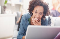 Smiling woman using laptop on sofa