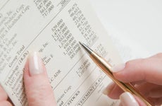 Close up a woman's hands holding a pen and a financial report.