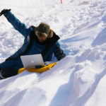 A person lying on top of a snow covered slope.