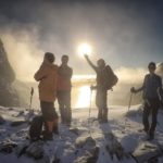 A group of people standing on top of a snow covered slope.