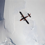 A person flying through the air on a snow covered slope.