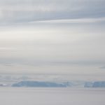 A group of clouds in the sky over a body of water.