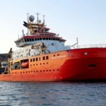 A large red ship in a large body of water