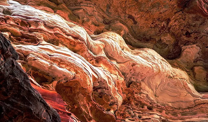 Close-up of swirling red and white rock formations resembling waves, highlighting texture and natural patterns.