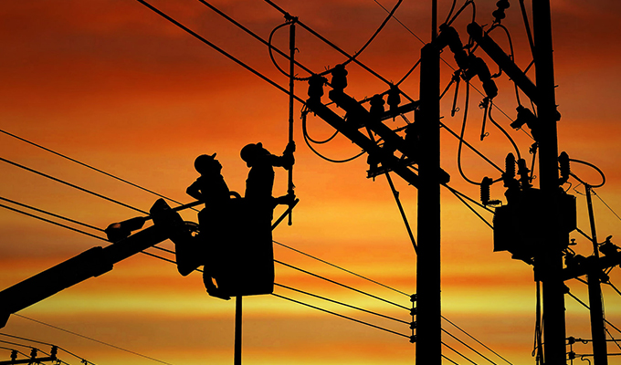 workers analyzing telephone poles back lite from sunset