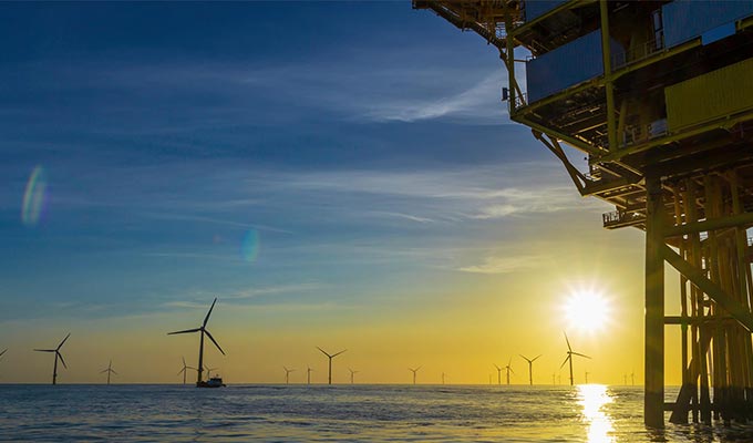 Wind turbines in the ocean at sunset.