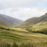 a green valley with a rainbow