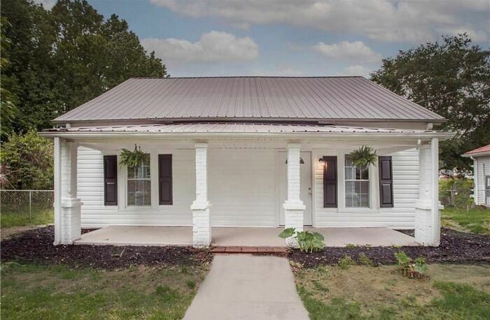 A house with uneven window placement and mismatched porch pillars, representing design disasters.