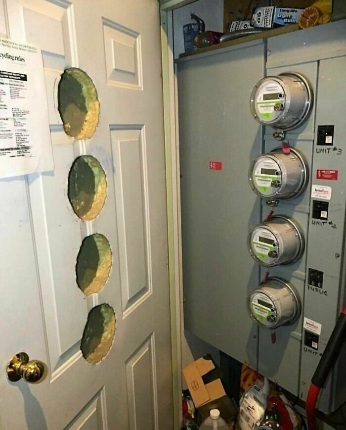 Design disasters: door with holes patched beside utility meters in a cluttered utility room.