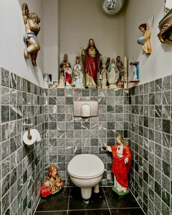 Bathroom design disaster with religious statues surrounding a toilet.