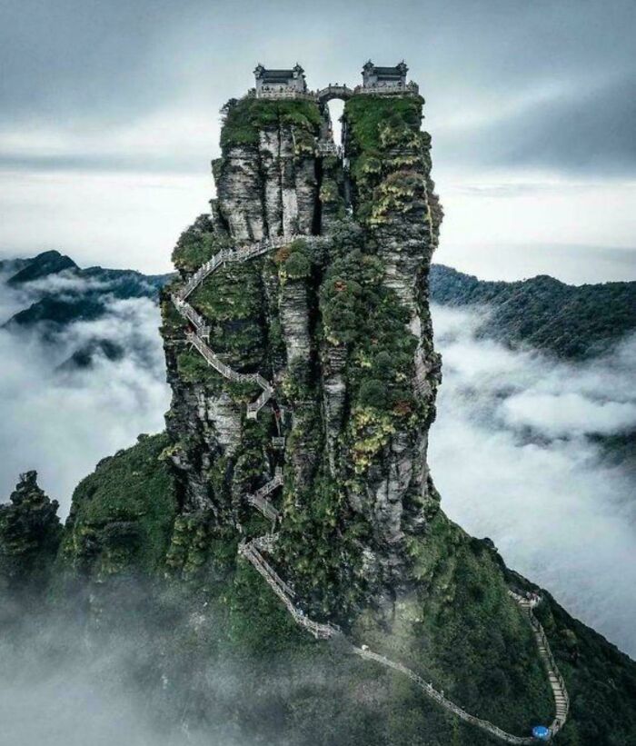 Gigantic rock formation with intricate stairway and temple, surrounded by misty mountains. Perfect for megaphobia themes.