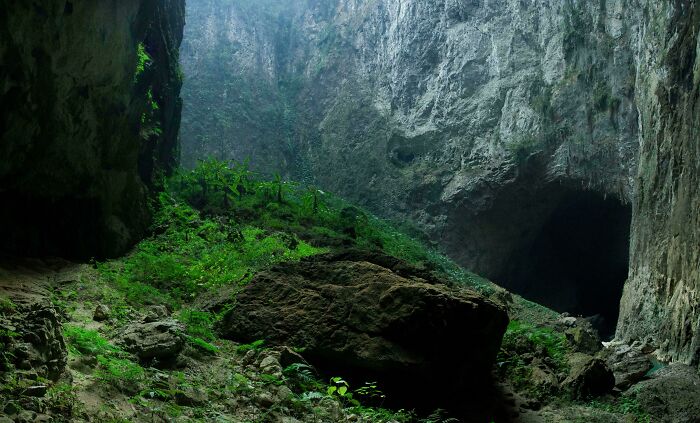 Check Out This Cave Entrance Chillin' At The Bottom Of A Sinkhole In Guizhou, China. Peep The Four Dudes On The Rock For Size Comparison