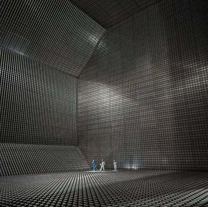 Tiny people inside a gigantic, grid-patterned chamber, exemplifying the concept of megalophobia.