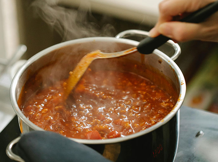 A person stirs a steaming pot of food, setting a trap for their food-thieving roommate.