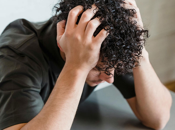 Person frustrated after food theft, holding head with hands.