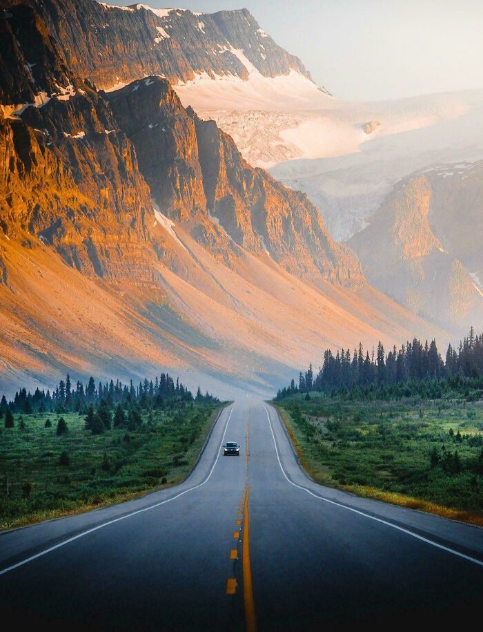 A winding road leads to massive, towering mountains—a striking view for those with megalophobia.