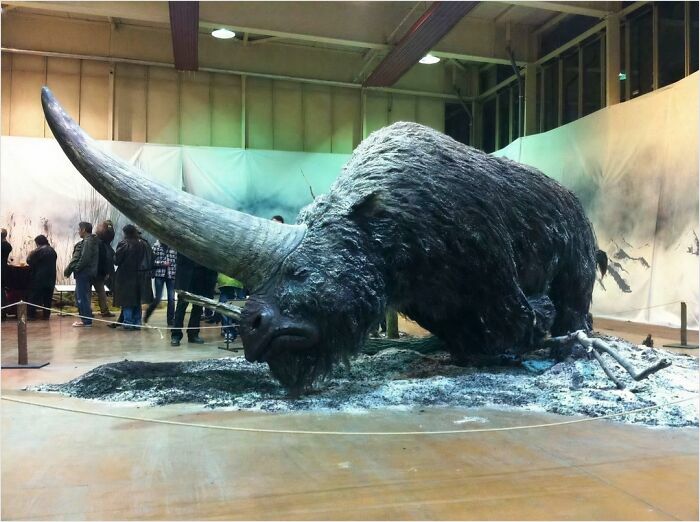 Massive horned creature exhibit captivating visitors, highlighting megalophobia triggers.