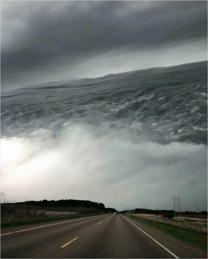 Massive cloud formation over a long, empty road, illustrating a scene triggering megalophobia.