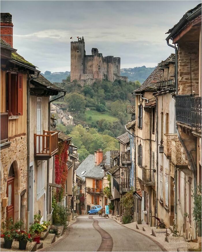 A gigantic castle looms over a quaint village street, creating a dramatic scene for those with megalophobia.