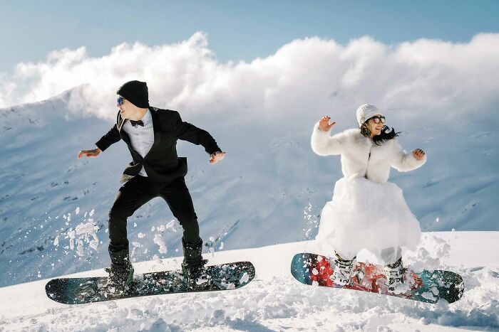 Bride and groom snowboarding in wedding attire, capturing a top 2024 wedding moment in the snowy mountains.