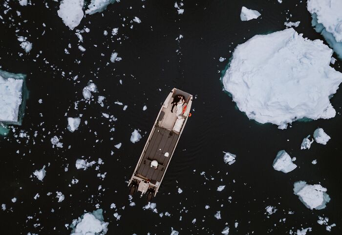 Aerial view of a couple on a boat surrounded by icebergs, capturing one of the top wedding photos of 2024.