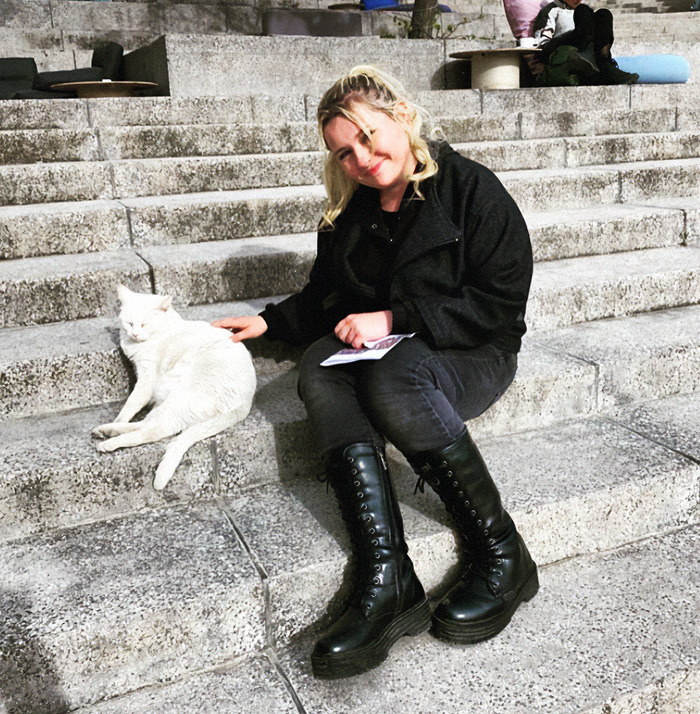 Abigail Breslin sitting on steps, petting a white cat.