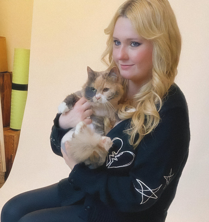 Abigail Breslin holding a cat, smiling gently at the camera.