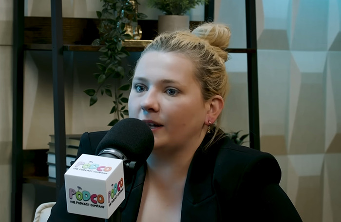 Abigail Breslin speaking into a microphone during a podcast recording.