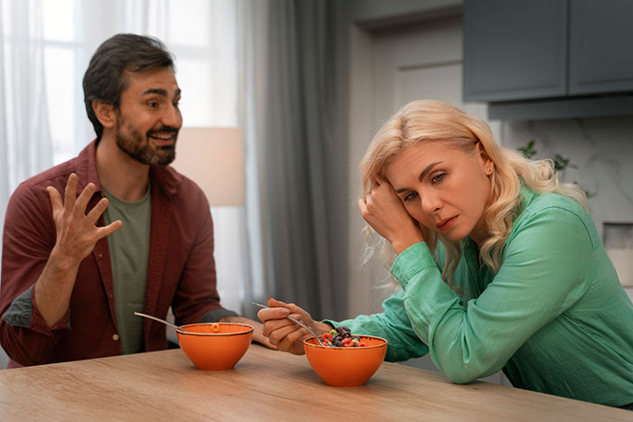 Woman discovering boyfriend's dark side after moving in, looking concerned during a meal at home.