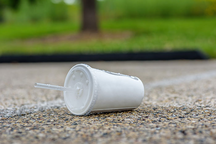 Discarded drink cup on pavement, symbolizing karma and consequences in a public setting.