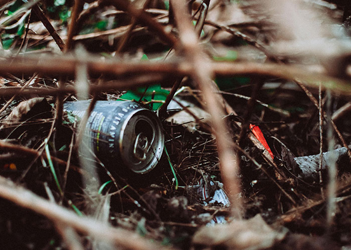 Discarded can in the bushes, a symbol for creative frugal hacks to save cash by repurposing waste.