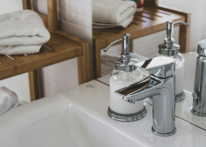 Bathroom sink with chrome faucet and soap dispenser, illustrating creative frugal hacks for home decor savings.