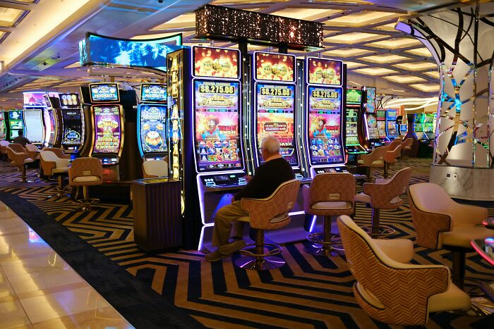 Casino employee seated at slot machine, showcasing behind-the-scenes atmosphere with colorful gaming displays.