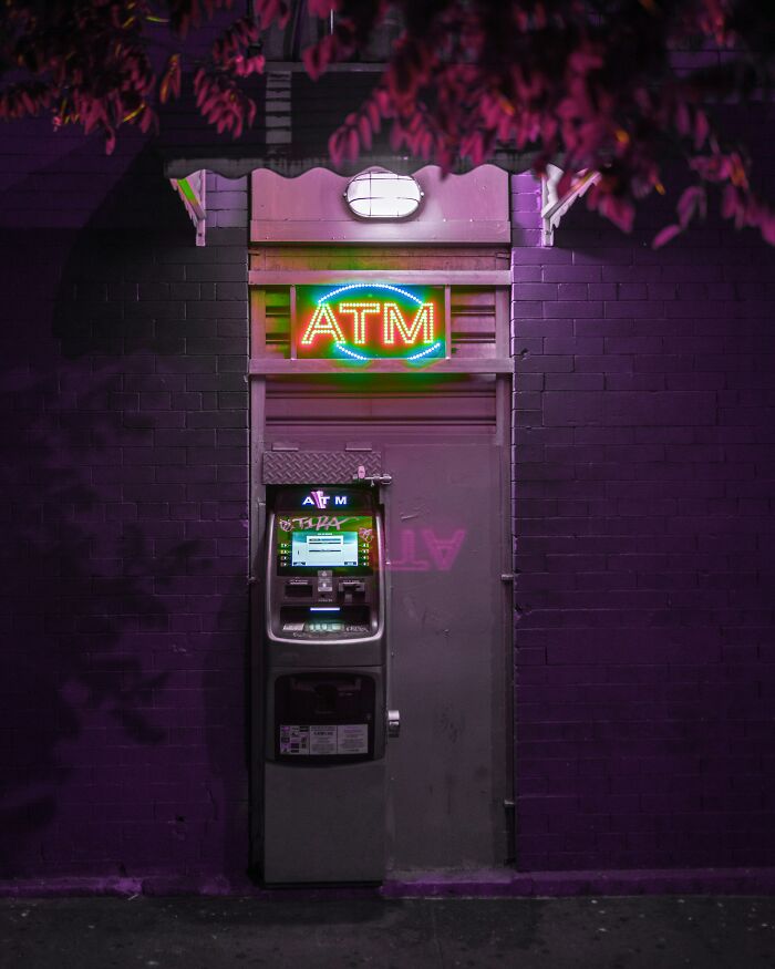 Neon ATM sign glowing in a dark alley, highlighting unseen casino operations.