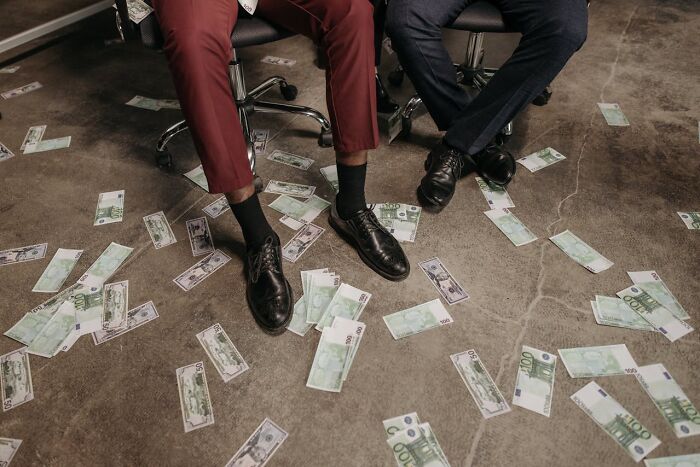 Casino employees' feet on a floor covered in cash, highlighting behind-the-scenes insights.