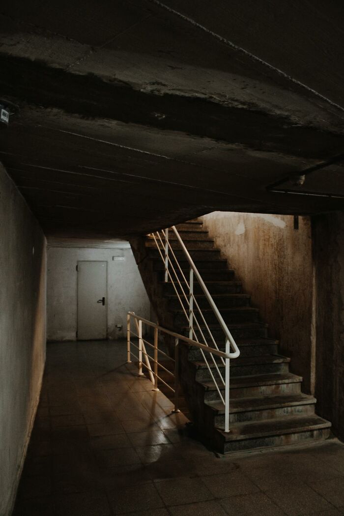 Dimly lit casino employee corridor with stairs leading to a basement area.