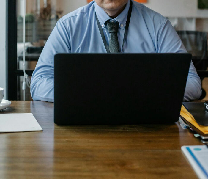 Casino employee in a blue shirt works on a laptop, offering a glimpse into behind-the-scenes activities.